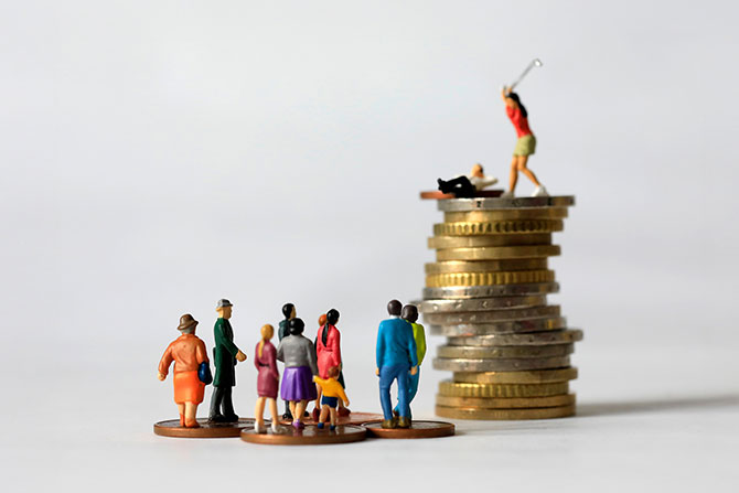The Mental Toll of Money Stress and How to Support Your Account Holders; A group of miniature figures stand on a flat surface, gazing at a stack of coins topped with a golfing figurine, illustrating wealth disparity.