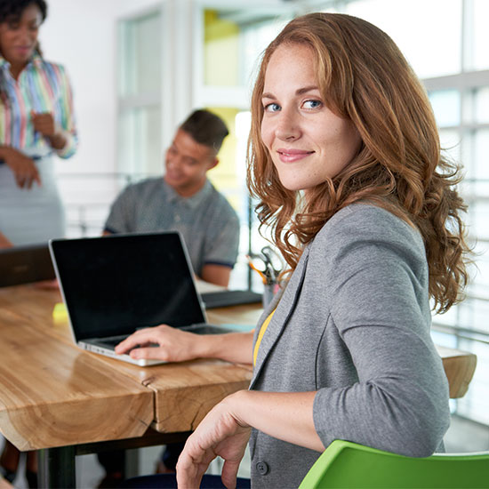 Woman with laptop at office table smiling