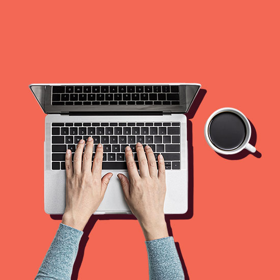 Person typing on computer with a cup of coffee